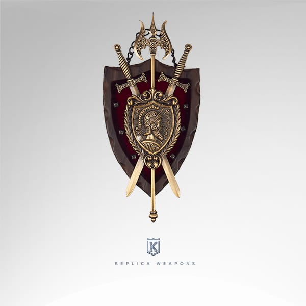 Réplica panoplia con escudo de armas decorado con un soldado mirando a la derecha, bajo es escudo se cruzan dos espadas y un hacha vikinga de doble filo. Acabado en metal dorado envejecido.